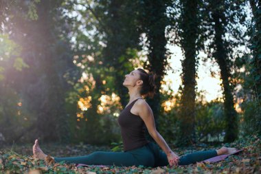 Maymun yoga pozu veren genç bir kadın.