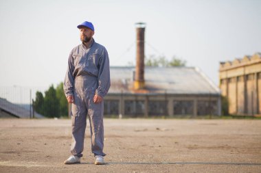 Fabrikanın önünde poz veren endüstriyel fabrika işçisi