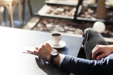 Adam açık kahve dükkanında kahve içiyor.