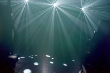 Birçok projektör boş bir sahneyi aydınlatıyor.