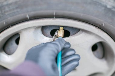 Lastiği hava basınçlı pompayla şişiriyor.