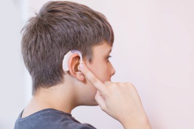 İşitme cihazı olan genç çocuk.