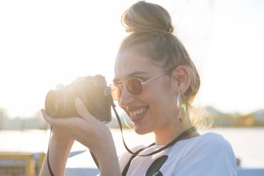 Genç bayan fotoğrafçı güpegündüz kamera kullanıyor.