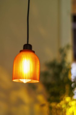 Sıcak turuncu kolye, akşam saatlerinde aydınlatılmış sıcak bir mekanda zarif bir şekilde asılı duruyor.