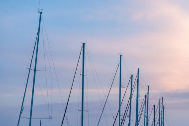 Yelkenli gün batımında pastel gökyüzüne karşı direkler