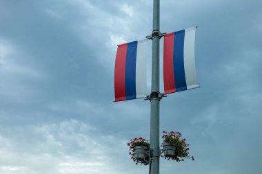 Şehir merkezinde bulutlu gökyüzünde dalgalanan iki Rus bayrağı