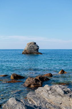 Sakin mavi sularla çevrili kayalık bir adanın sakin manzarası berrak bir gökyüzünün altında