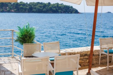 Güneşli bir günde sakin mavi suların kıyısında huzurlu bir sahil manzarası.