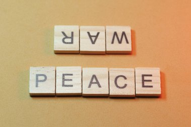 Barış ve savaş sarı arka planda tahta bloklarla yazılır.