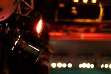 Işıklandırma ekipmanları, canlı bir tiyatro ortamındaki bir akşam etkinliği sırasında bir performans sahnesini aydınlatıyor