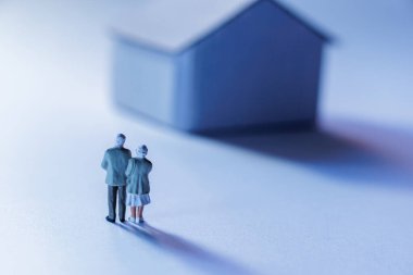 Minyatür bir evin yanında yan yana duran yaşlı çift figürleri yumuşak, rüya gibi bir ortamda anılarını yansıtıyorlar.