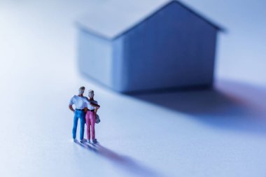 Minyatür bir evin önünde sevgi ve ev hayatını sembolize eden minyatür figürler.