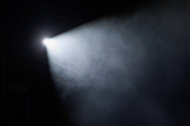 Işık demeti, karanlık uzayı dumanla aydınlatır ve gece atmosferik bir etki yaratır.