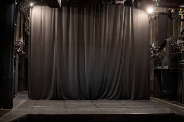 Siyah perdeli karanlık tiyatro sahnesi gösteriye hazır.