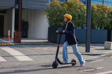 Şehir caddesinde elektrikli scooter kullanan biri.