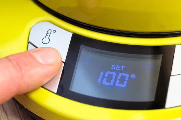 Person setting electric tea kettle temperature to 100 C — Stock Photo, Image