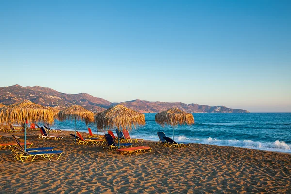 Вечерний пляж с шезлонгами и зонтиками — стоковое фото