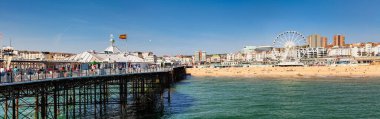 BRIGHTON, İngiltere - 5 Haziran 2013: Güneşli bir yaz gününde Brighton Palace Rıhtımı 'ndan çekilmiş Ferris Wheel gezinti güvertesi ve taverna plajı ile sahil manzarası