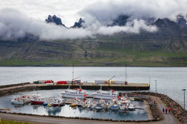 Stodvarfjordur, İzlanda - 2 Ağustos 2015: Küçük balıkçı limanına demirlemiş gemiler. Arka planda manzara dağları görülüyor