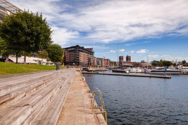 OSLO, NORway - 23 Temmuz 2018: Yenilenmiş Tjuvholmen liman bölgesinde iskele, Aker Brygge Mahallesi ve marina arka planda görüldü