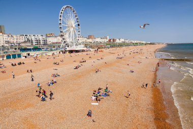 BRIGHTON, İngiltere - 5 Haziran 2013: Güneşli bir yaz gününde Brighton Sarayı İskelesi 'nden çekilen, Brighton Sahili boyunca dönme dolap ve turistle birlikte gezin.