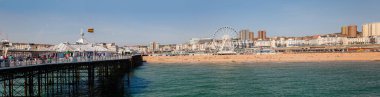BRIGHTON, İngiltere - 5 Haziran 2013: Güneşli bir yaz gününde Brighton Palace Rıhtımı 'ndan çekilmiş Ferris Wheel gezinti güvertesi ve taverna plajı ile sahil manzarası