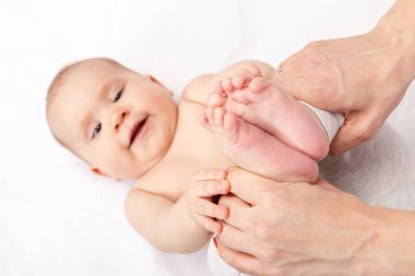 Pediatri kliniğinde altı aylık bir kızla fizyoterapist geliştirme egzersizi yapıyor. Doktor ayak bileklerinin, kalçalarının ve dizlerinin esnekliğini arttırmak için çocukların bacaklarını manipüle ediyor.