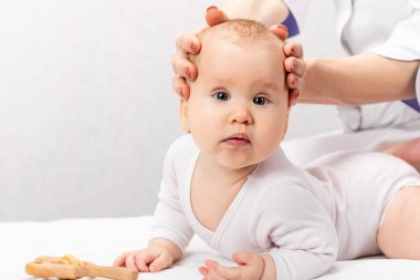 Altı aylık bebek, pediatri kliniğinde osteopatik veya kayropraktik tedavi görüyor. El terapisti çocukların kafasını ve boynunu manipüle ediyor.