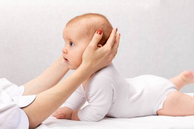 Altı aylık bebek, pediatri kliniğinde osteopatik veya kayropraktik tedavi görüyor. El terapisti çocukların kafasını ve boynunu manipüle ediyor.