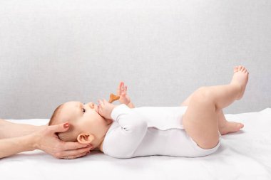 Altı aylık bebek, pediatri kliniğinde osteopatik veya kayropraktik tedavi görüyor. El terapisti çocuğun kafasını ve boynunu manipüle ediyor.