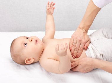 Kadın çocuk doktoru ya da sağlık uzmanı, bebeğin karnını muayene eder. Doktor elle muayene ediyor. Çocuk fiziksel muayene kavramı