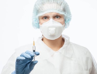 Close-up shot of doctor wearing PPE protective suit, goggles and FFP3 face mask holding syringe ready for injection of a vaccine or medicine