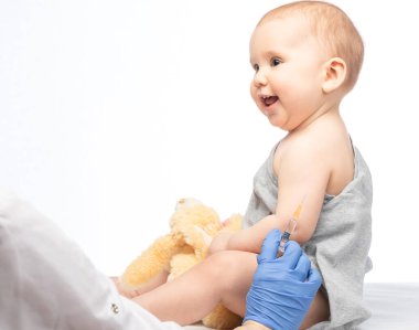 Pediatrician or nurse ready to give an intramuscular injection of a vaccine to a baby girl during coronavirus COVID-19 pandemic