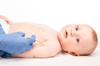 Pediatrician or nurse giving an intramuscular injection of a vaccine to arm of a baby boy during coronavirus COVID-19 pandemic