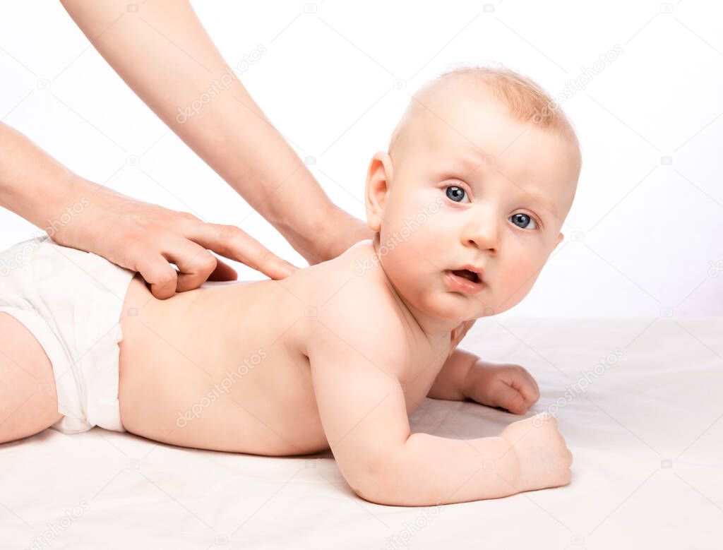 Five month baby boy receiving massage therapy in pediatric clinic. Manual therapist manipulates childs's spine
