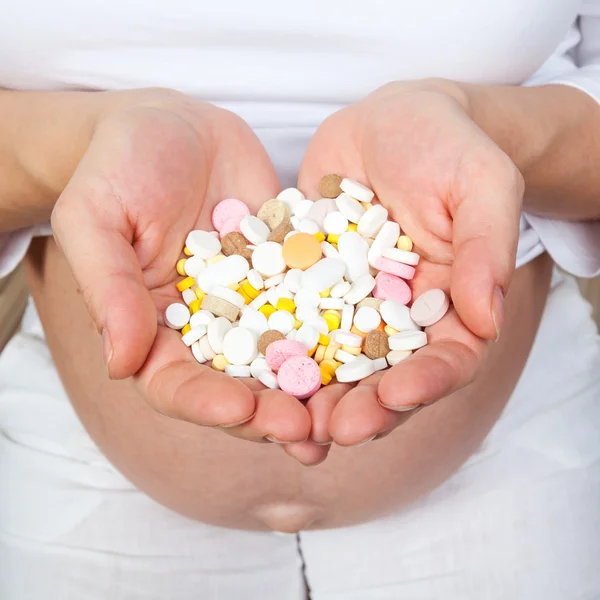 Mujer embarazada mostrando pastillas —  Fotos de Stock