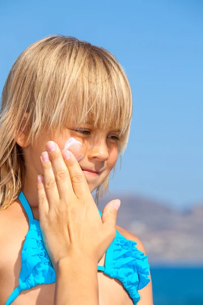 Moeder zonnebrandcrème toe te passen op haar gezicht childs — Stockfoto