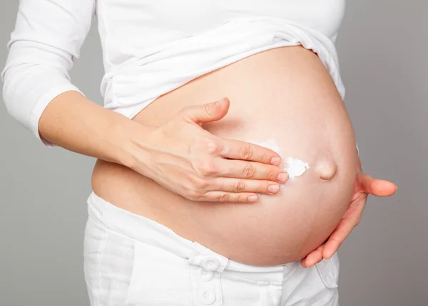 Mujer embarazada aplicando crema en el vientre — Foto de Stock