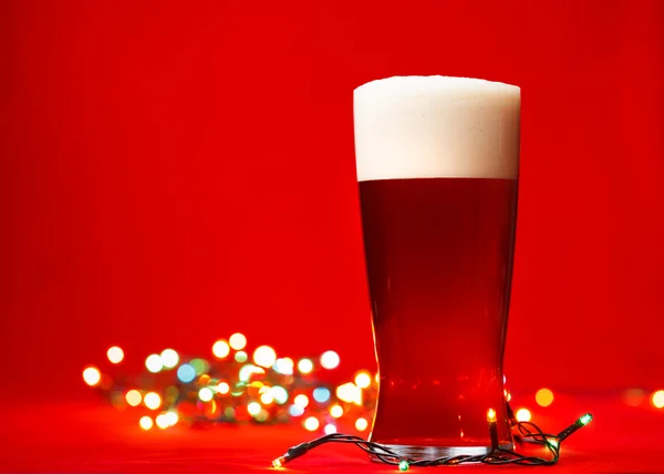 Vol glas beer of ale met Kerstverlichting op rode achtergrond — Stockfoto