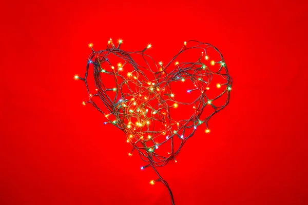 Heart shaped Christmas lights on red — Stock Photo, Image
