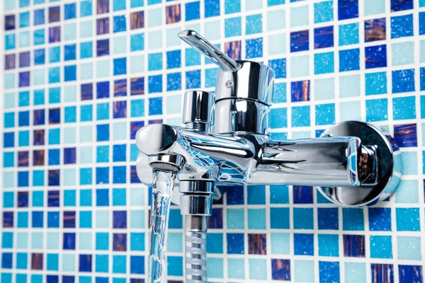 Rubinetto vasca da bagno su una parete piastrellata blu — Foto Stock