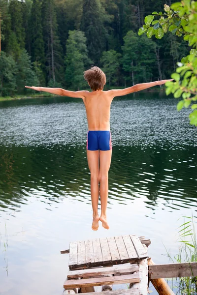 Un gamin saute d'un quai en bois — Photo