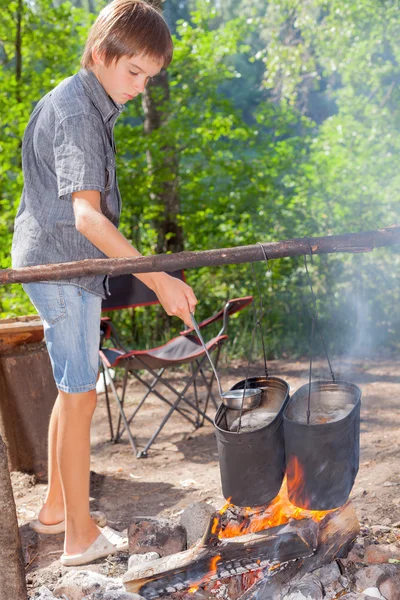 Boy cooking on campfire — Stock Photo, Image