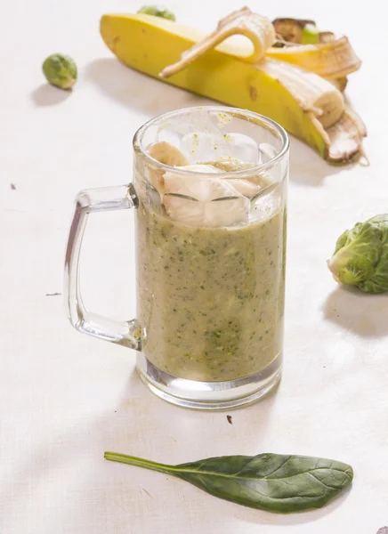 Verre de smoothie avec des feuilles de banane brocoli et menthe — Photo