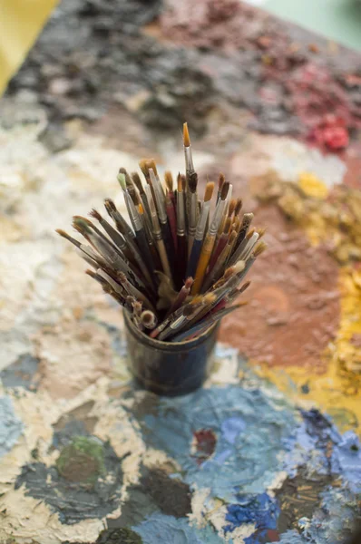 Painters brushes on palette of dry oil colors — Stock Photo, Image