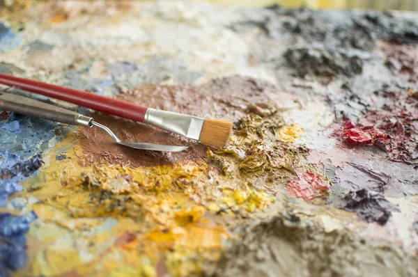 Close up of focused trowel and brush on painting palette — Stock Photo, Image