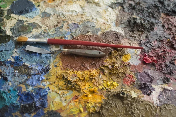 Oil paint on palette with trowel and brush on it — Stock Photo, Image