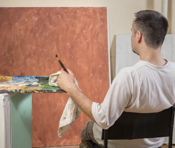 Painters back while sitting and analyzing his work — Stock Photo, Image