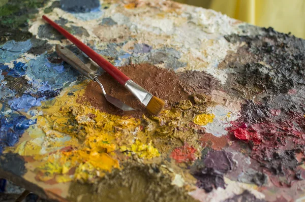 Focused trowel and brush on oil paint palette — Stock Photo, Image