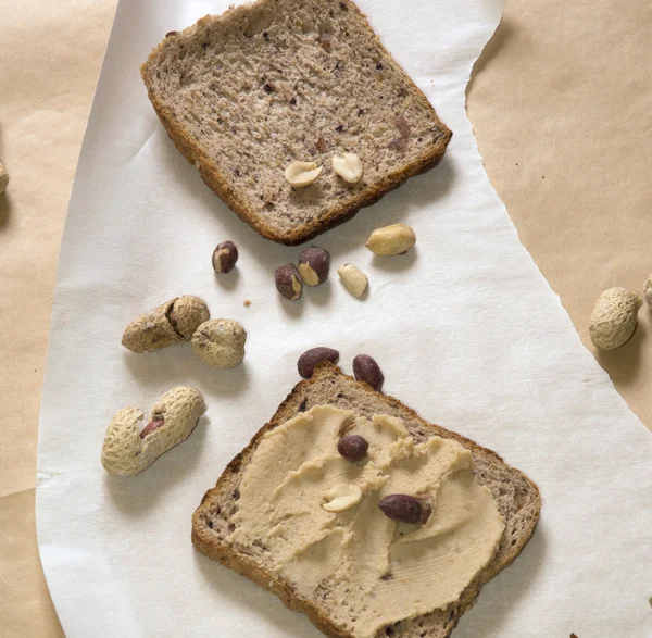 Pan de cacahuete con mantequilla de cacahuete y cacahuetes sobre papel —  Fotos de Stock